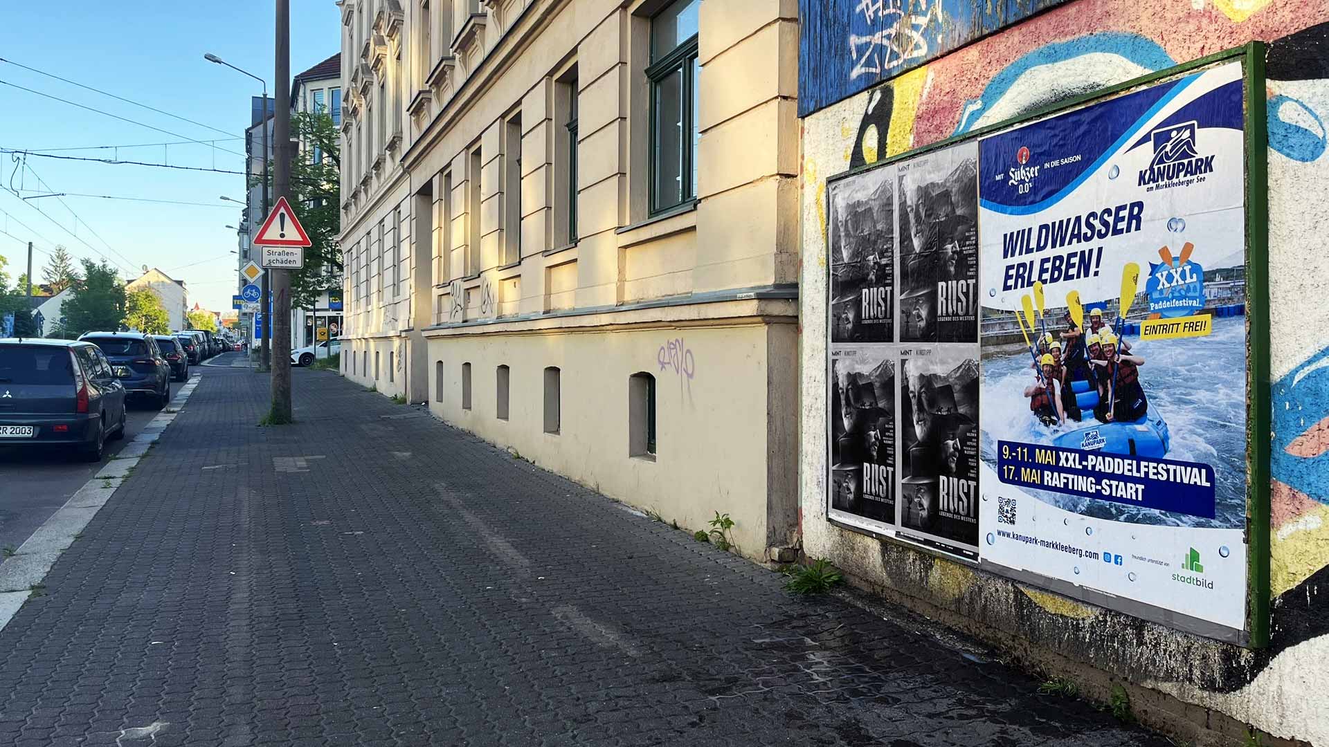 Plakat mit Informationen zu einem Wildwasser-Paddel-Festival an einer Wand in einer Stadt.