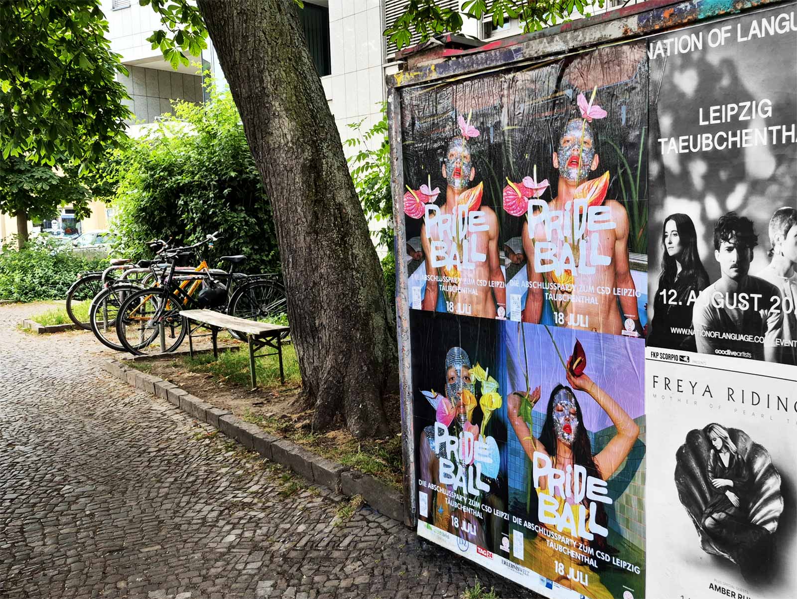 Bunte Prideball-2026-Plakate hängen an einer Wand in Leipzig, daneben ein schwarz-weißes Veranstaltungsplakat.